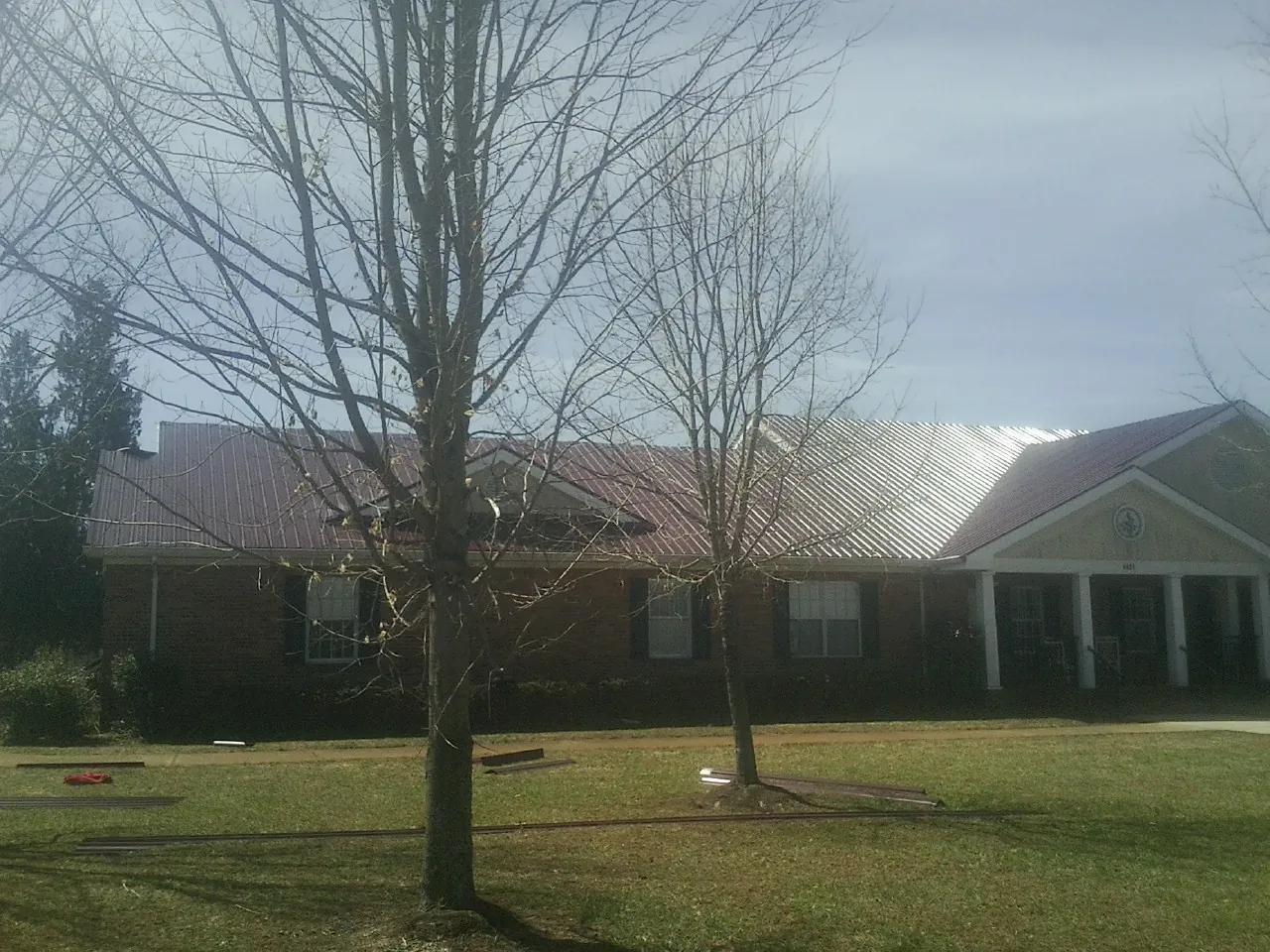 Red metal roof on a brick building seen from the front lawn in Glenwood